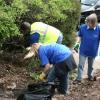 Volunteers work to prune back and clear away vegetation that has overgrown the footpaths.