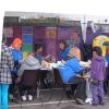 The face painters had a never-ending queue of children who wanted their faces painted.